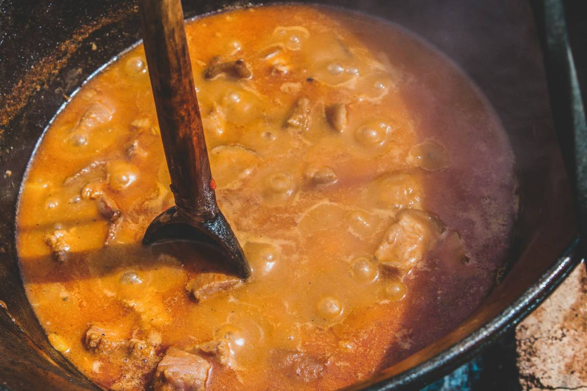 Ensopado borbulhando em panela de ferro com colher de pau