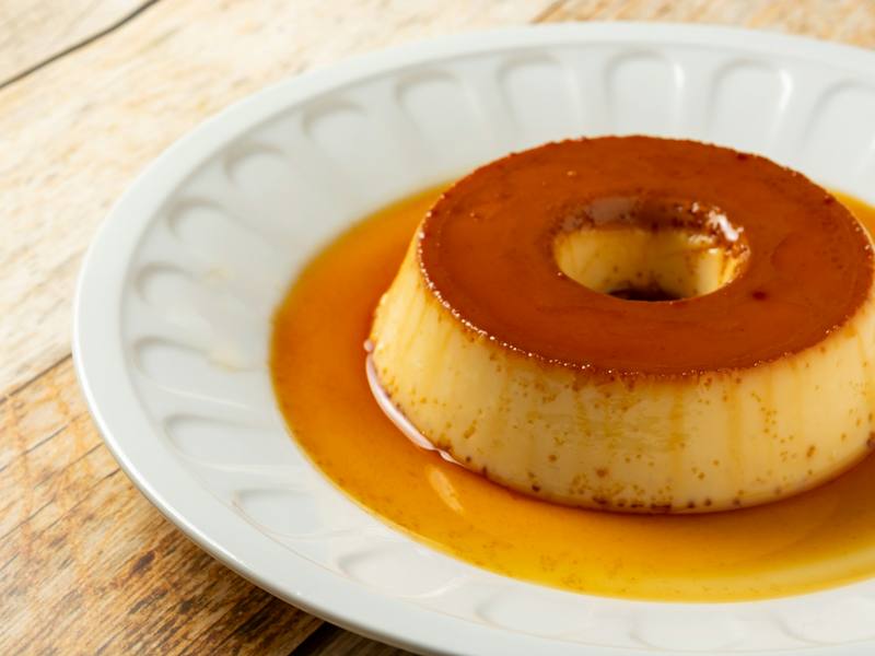Pudim de leite com calda de caramelo em prato branco