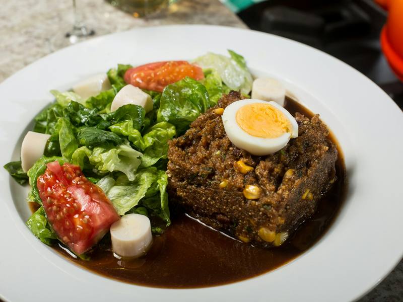 Farofa úmida com milho e ovo cozido ao lado de salada de alface, tomate e palmito